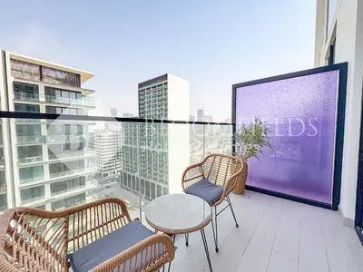 a balcony with two chairs and a table and a large screen at Bloomfields Cozy 1Br Binghatti House in Dubai