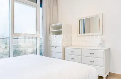 a bedroom with a white bed and a mirror at Bloomfields Spacious 1br Bloom Tower in Dubai