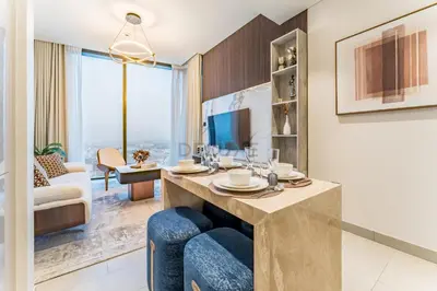 a living room with a dining table with blue chairs at High Floor, Few Steps From Dubai Canal and Waterfront Promenade, Sobha Hartland Waves, Sobha Hartland by Deluxe Holiday Homes in Dubai
