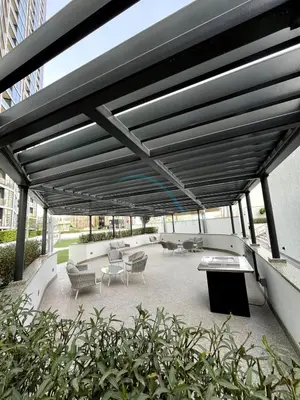 a covered patio with chairs and tables on a building at High Floor, Few Steps From Dubai Canal and Waterfront Promenade, Sobha Hartland Waves, Sobha Hartland by Deluxe Holiday Homes in Dubai