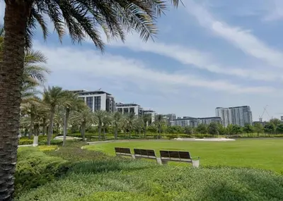 two benches in a park with palm trees and buildings at New Luxury 1 Bed - Opposite Dubai Hills Mall in Dubai