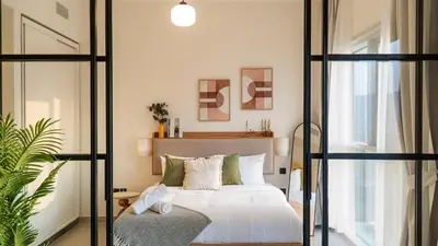 a bedroom with a white bed and a chair at New Luxury 1 Bed - Opposite Dubai Hills Mall in Dubai