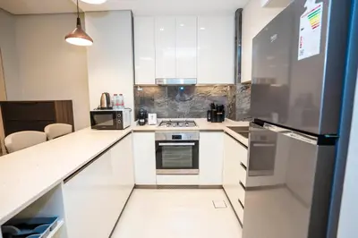 a kitchen with white cabinets and a refrigerator at Highlife Haven in Dubai with Pool and Gym in Dubai