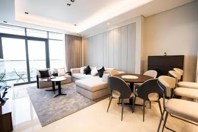 a living room with a couch and a table and chairs at Cityscape Retreat Nobles 2BR Nobles Edition in Dubai