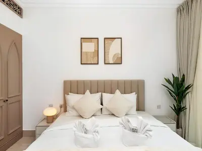 a bedroom with a large white bed with two pillows at Luxury 2BR- Pool with Burj View- 2 Min to Dubai Mall in Dubai