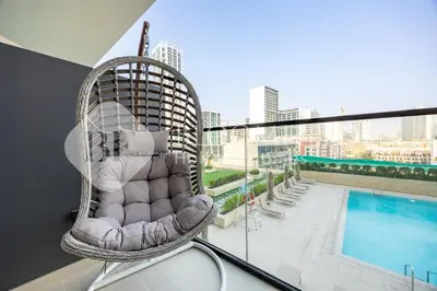 a rattan chair sitting on a balcony next to a pool at Bloomfields Modern 1Br Binghatti Onyx in Dubai