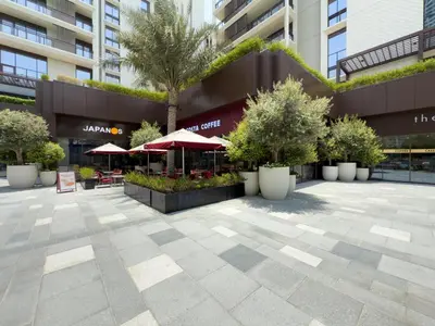 a courtyard in front of a building with trees and umbrellas at GuestReady - Charming stay at Creek Beach in Dubai