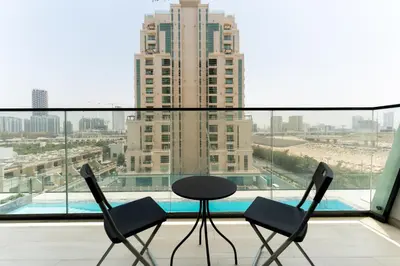 a table and two chairs on a balcony with a view at Smart Home 1BR with Pool and City View in JVC by Bhavan Vacation Homes in Dubai