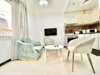 a living room with two chairs and a table at Homes2Retreat - Modern Studio with Balcony in JVT in Dubai