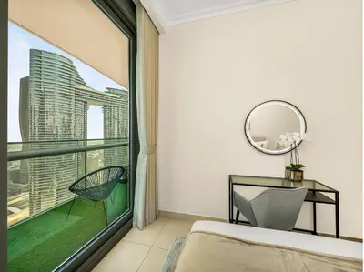 a bedroom with a large window and a chair at Kensington 2BR walk to Dubai Mall via Link in Dubai