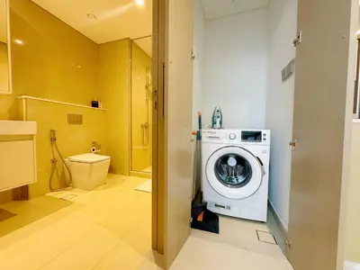 a bathroom with a washing machine and a toilet at Stylish & Comfy Downtown Oasis Views, Pool & Gym in Dubai