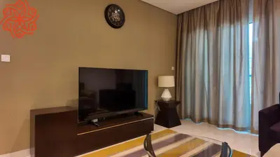 a living room with a television and a clock on the wall at Amazing 1bdr apartment in business bay in Dubai