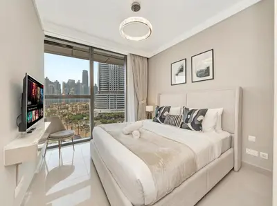 a white bedroom with a large bed and a window at Kensington 1BR and Study with Sofa Bed Burj View Dubal mall link in Dubai