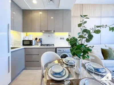 a kitchen and a dining room with a table and chairs at Serene Luxe l Modern 1BR in Meydan with Pool in Dubai
