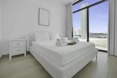 a white bed in a room with a large window at BLVD Boutique Style Apartment Gym Pool Balcony JVC in Dubai