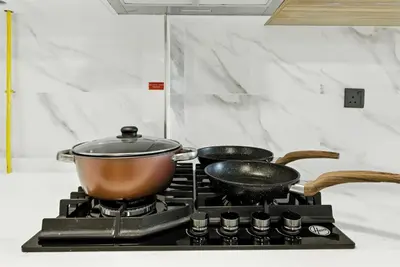 two pots and pans on a stove in a kitchen at BLVD Boutique Style Apartment Gym Pool Balcony JVC in Dubai