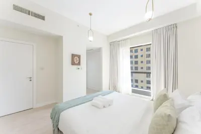 a white bedroom with a large white bed and a window at Veluxa - Beautiful 2Bed in JBR in Dubai