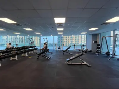 a gym with treadmills and people exercising in it at Marina View, 2BR Ideal for Groups, Walk to beach in Dubai