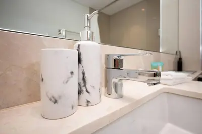 a bathroom sink with a soap dispenser on a counter at High-Rise Apartment by Burj and Fountain in Dubai