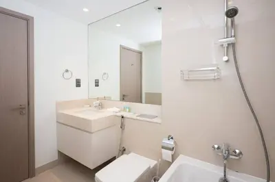 a white bathroom with a sink and a mirror at High-Rise Apartment by Burj and Fountain in Dubai