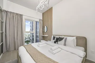 a bedroom with a large white bed with a window at Modern 2BR Golfville Dubai in Dubai