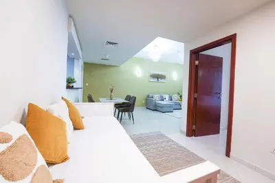 a living room with a white couch and a dining room at Best Deal I Spacious Apartment I Full Amenities including Balcony, Pool, Gym, Kids Play Area in Dubai