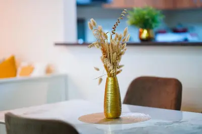 a yellow vase with dried flowers in it on a table at Best Deal I Spacious Apartment I Full Amenities including Balcony, Pool, Gym, Kids Play Area in Dubai