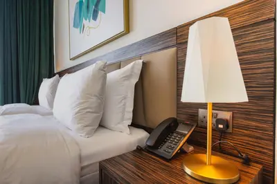 a hotel room with a bed with a lamp and a phone at Maison Privee - Chic Coastal Escape with Open Sea Vws on Palm Entry in Dubai