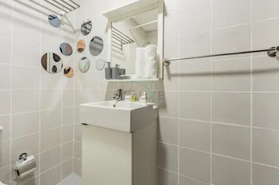 a white bathroom with a sink and a mirror at Studio Steps from JBR Beach and Marina Walk, Conveniently located near Ain Dubai, Dec Towers T2, Dubai Marina by Deluxe Holiday Homes in Dubai
