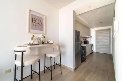 a kitchen with a bar with stools and a refrigerator at Frank Porter - Bloom Tower C in Dubai