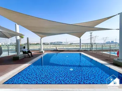 a large swimming pool under a large white umbrella at Elegant 1BR at Azizi Riviera l Prime Location in Dubai