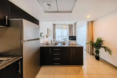 a kitchen with black cabinets and a refrigerator at 1BD Canal View for 4 in Bay Central, Dubai Marina in Dubai