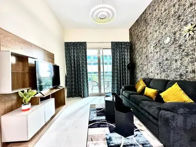 a living room with a black couch and a tv at Stylish 1 Plus Maid's 5 mins to Metro at Marina Park in Dubai