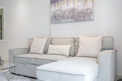 a couch and a ottoman in a living room at Stylish 1BR DunyaTower Apartment 2min to DubaiMall in Dubai