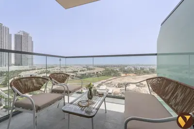 a balcony with chairs and a table and a view of the city at Vogue Damac Hills Golf Gate near First Avenue Mall, Two Bedroom Apartment with Balcony and Vibrant Community View, Access to all Amenities in Dubai