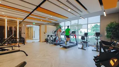 two people exercising in a gym with cardio equipment at Vogue Damac Hills Golf Gate near First Avenue Mall, Two Bedroom Apartment with Balcony and Vibrant Community View, Access to all Amenities in Dubai