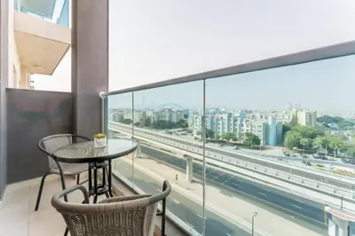 a table and chairs on a balcony with a view of a city at Few Metres Walk to Metro, Minutes Drive from Ibn Battuta Mall, Victoria Residency, Al Furjan by Deluxe Holiday Homes in Dubai