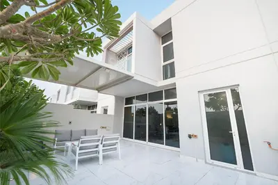 a white house with glass doors and a patio at EasyGo-Elavated Urban Living Stylish 3Bedroom townhouse in Dubai
