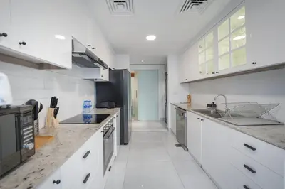 a large kitchen with white cabinets and appliances at EasyGo-Elavated Urban Living Stylish 3Bedroom townhouse in Dubai