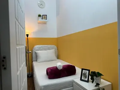 a small room with a bed with a chair and a clock at Smart Partition Room Barsha ! in Dubai