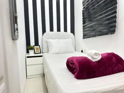 a white bed with a purple pillow on it at Beautiful Partition Room in Al Barsha 1 in Dubai