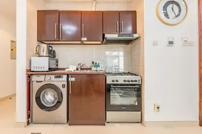 a kitchen with a stove and a washing machine at Studio Near Dubai Water Canal and Bus Station, Conveniently Close to Downtown, The Scala Tower, Business Bay by Deluxe Holiday Homes in Dubai