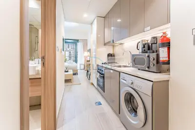 a kitchen with a washing machine and a sink at Modern Studio Near Downtown Dubai, Few Mins Walk to Hartland Greens Park, Azizi Riviera 43, Al Merkadh by Deluxe Holiday Homes in Dubai