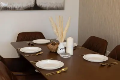 a wooden table with plates and utensils on it at Luxury 2BHK in Jumeirah Lakes Towers Icon 3502 in Dubai