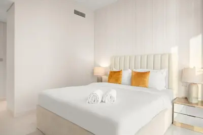 a bedroom with a large white bed with two shoes on it at FIRST CLASS 2BR Sea & Palm View, Beachfront in Dubai