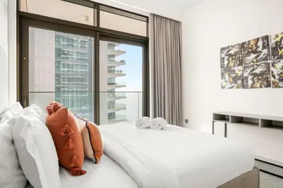 a bedroom with a white bed and a large window at FIRST CLASS 2BR Sea & Palm View, Beachfront in Dubai