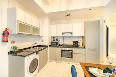 a kitchen with white cabinets and a washer at Convertible 1BR with Canal and Skyline View by BMS in Dubai