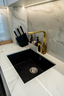 a bathroom sink with a gold faucet on a counter at Homes & Beyond l Serene 1BR Retreat in JVC in Dubai