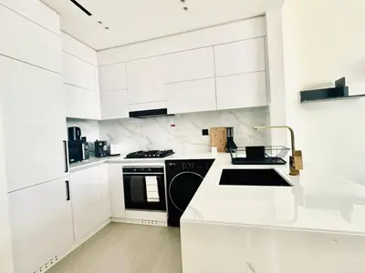 a white kitchen with black appliances and white cabinets at Crisp And Curated 1br With Pool, Gym And Parking! in Dubai