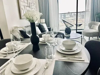 a dining room table with plates and a vase of flowers at Crisp And Curated 1br With Pool, Gym And Parking! in Dubai